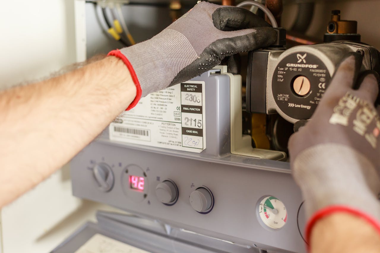 contact-img-02 Close-up of hands adjusting a boiler system with precise instrumentation, showing maintenance work.